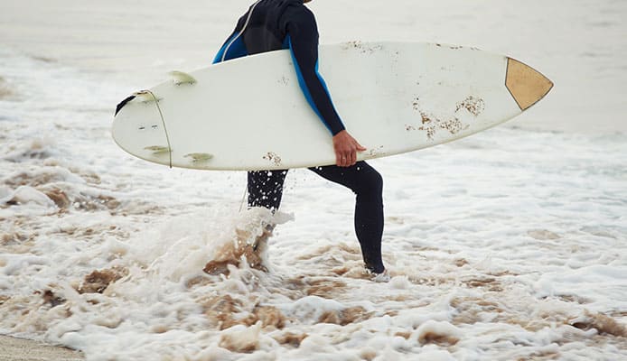 Professional_surfer_holding_his_surfing_board_walking_on_the_beach